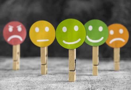 Five faces with different emotions on wooden pegs