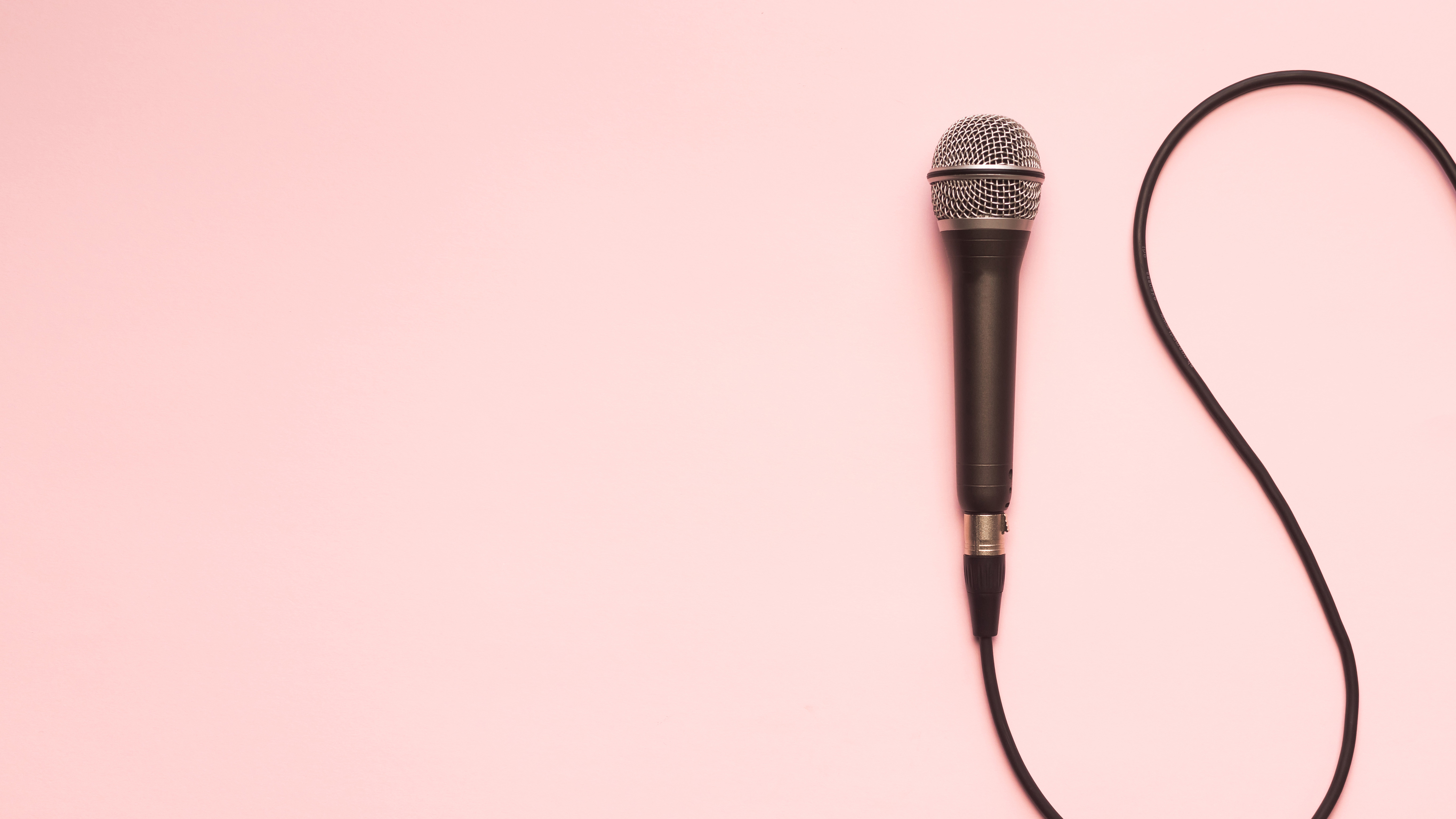 Photograph of a microphone and cable on a pink surface