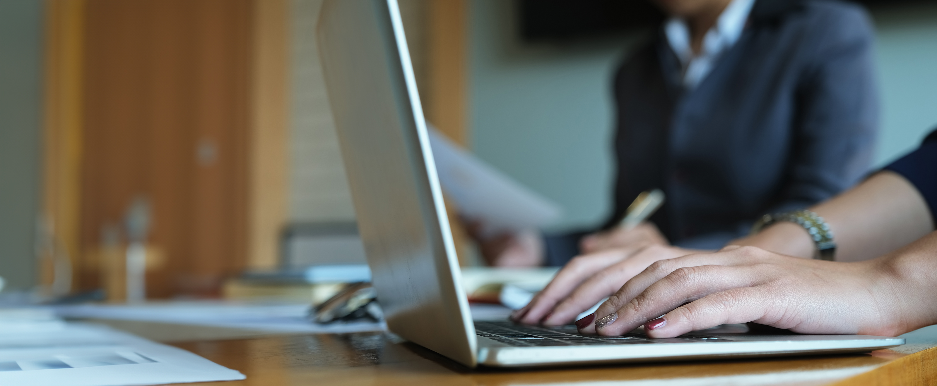 Close up photo of someone's hands on a laptop keyboard 