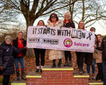 Photo of a group of people holding a banner that says 'It starts with Men - White Ribbon Day - Salcare'