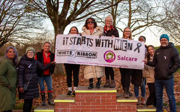 Photo of a group of people holding a banner that says 'It starts with Men - White Ribbon Day - Salcare'