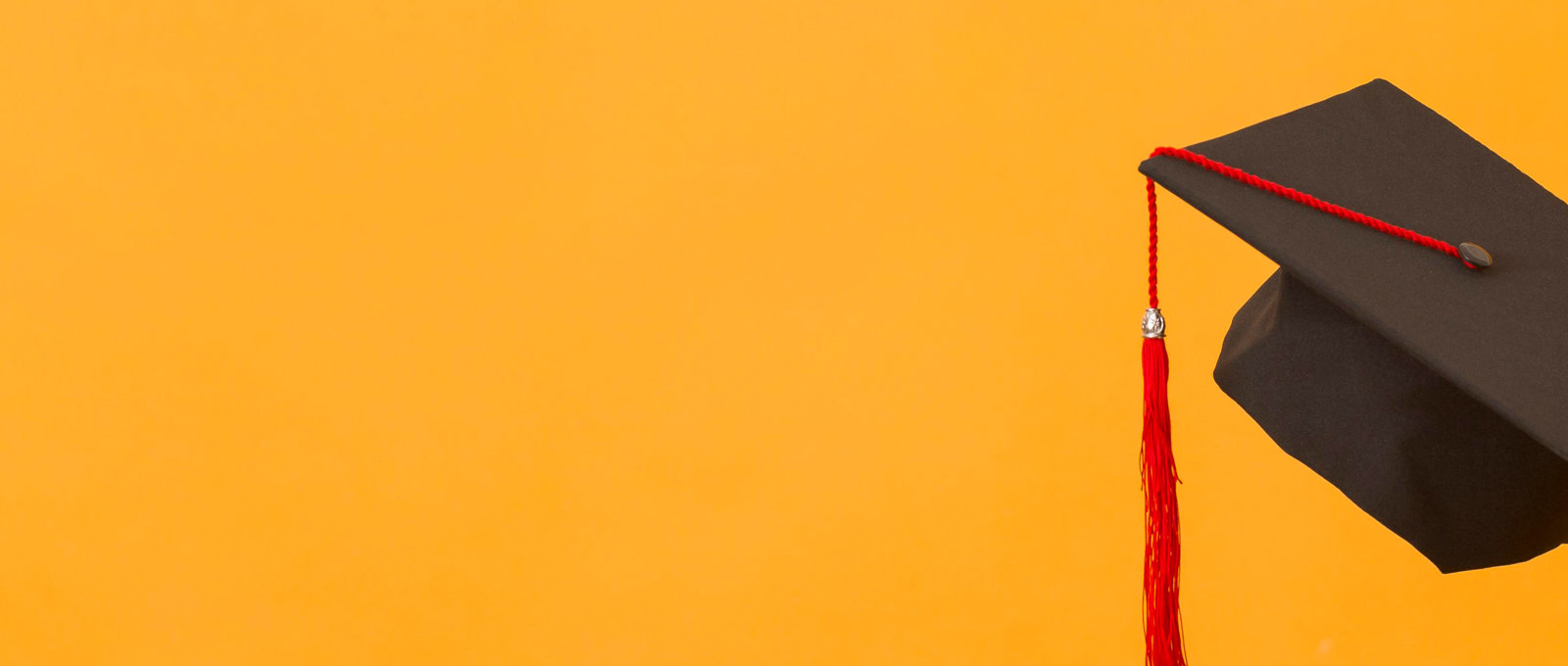 Close-up photo of a graduate's mortar board against an orange background