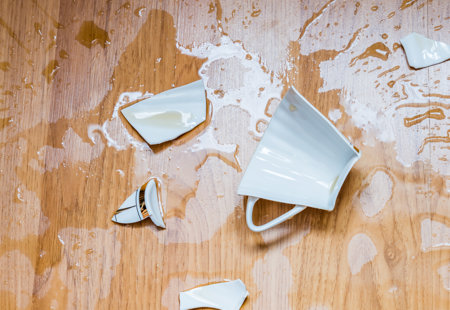 A broken tea cup on a wooden floor.