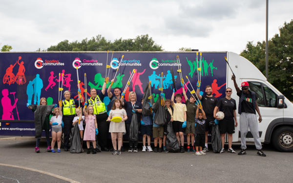 Group of partners and children with litter pickers and sports equipment