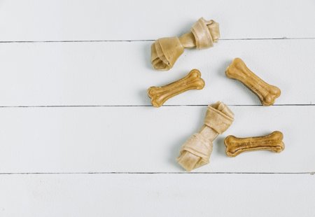 Five chewing dog bones on a white wooden background