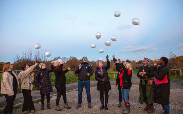Photo of a group of people letting go of balloons