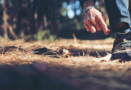 Man Tying Up Walking Shoes In A Forest Banner