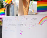 A canvas reading "What does Pride in your community mean to you" in rainbow colours, surrounded by Pride flags