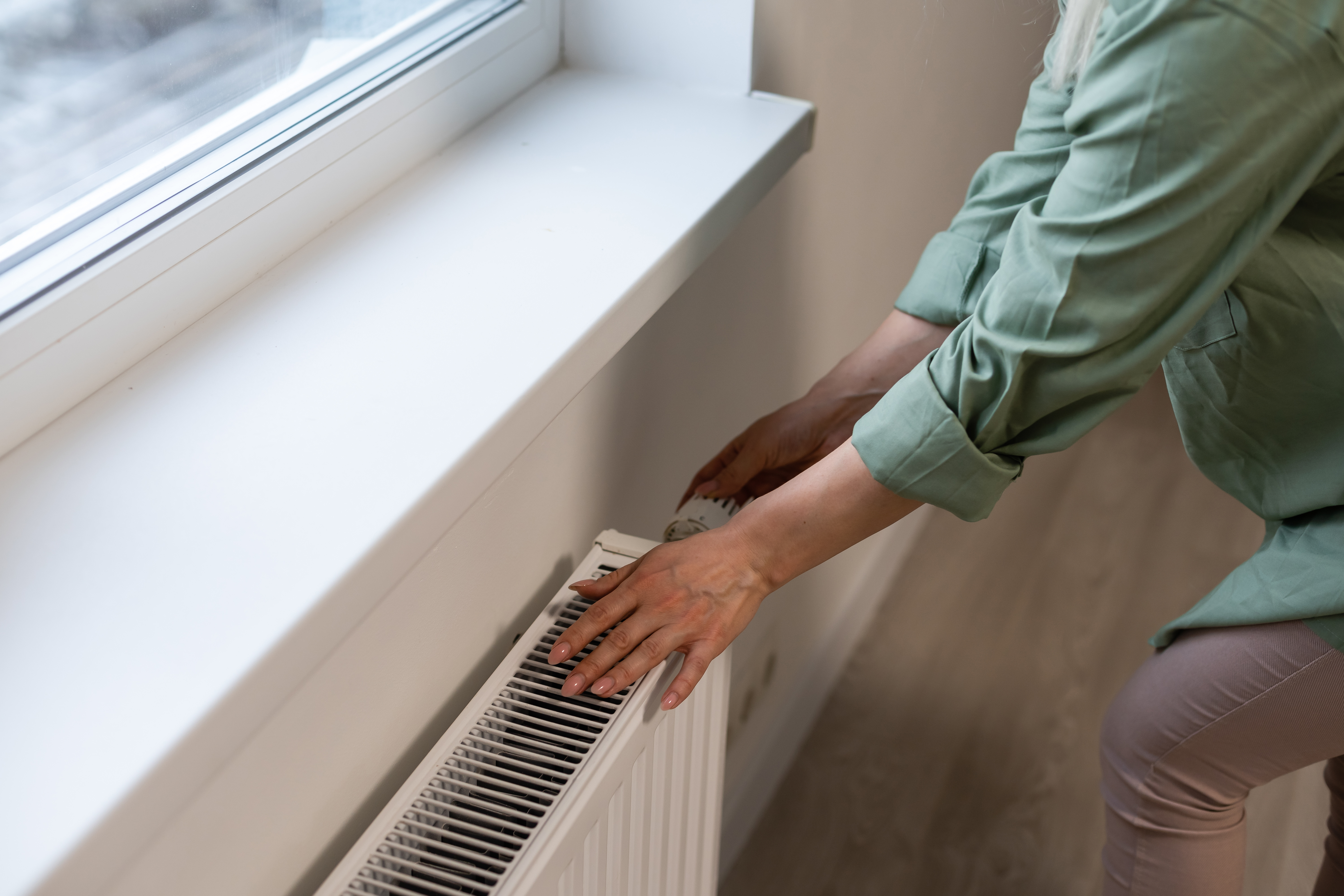 Close-up of woman's hand adjusting radiator thermostat