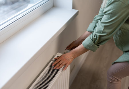 Close-up of woman's hand adjusting radiator thermostat