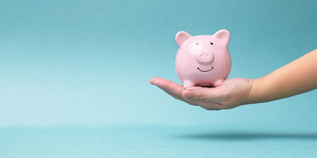 Hand Holding Pink Smiling Piggy Bank, Blue Background