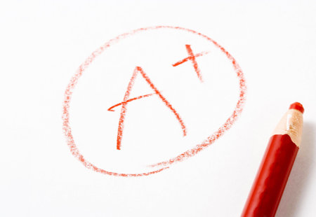 Photo of 'A+' written in red pencil on white paper with the pencil lying next to the writing