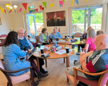 Customers and colleagues sat around tables inside a community centre