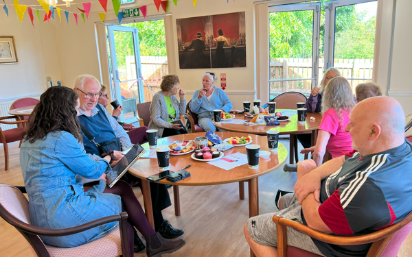 Customers and colleagues sat around tables inside a community centre