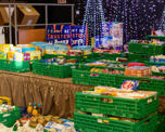 Crates of food on a stage with Christmas decorations in the background