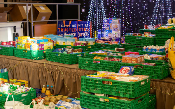 Crates of food on a stage with Christmas decorations in the background