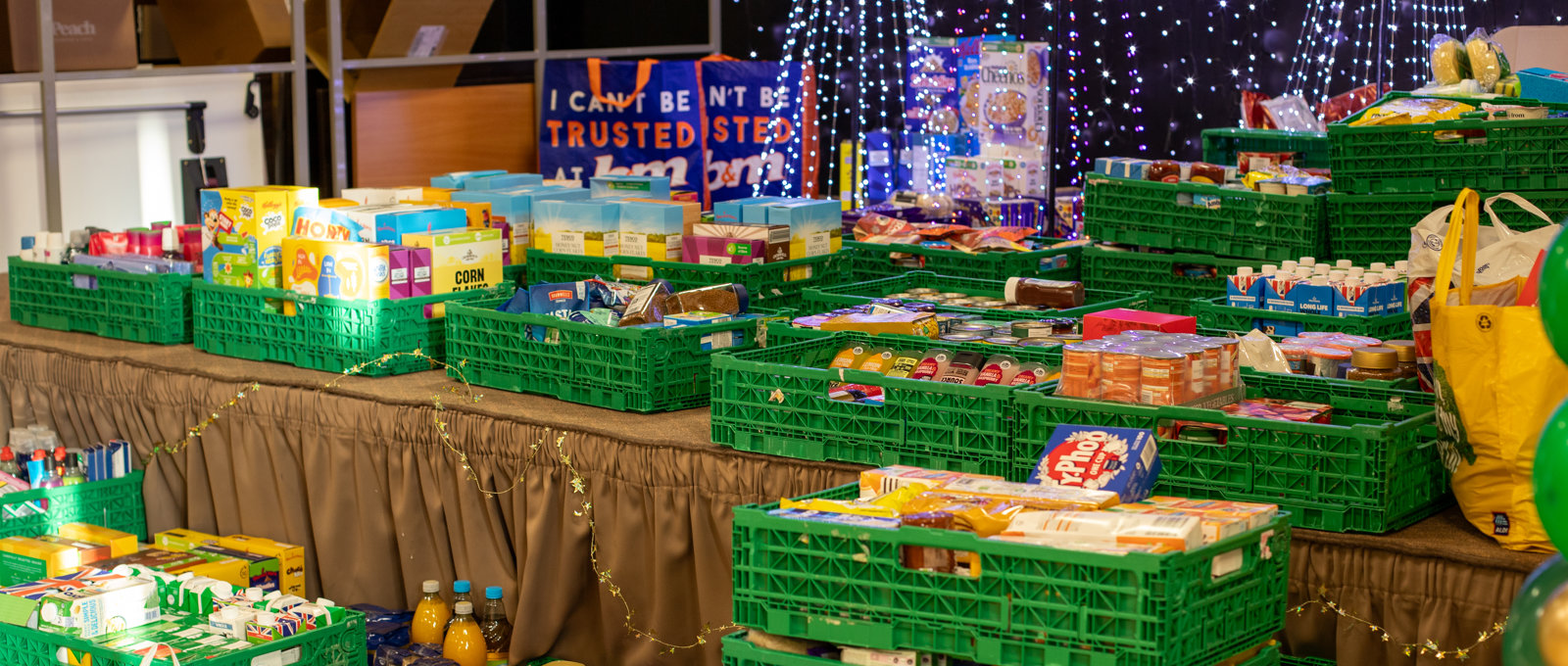 Crates of food on a stage with Christmas decorations in the background