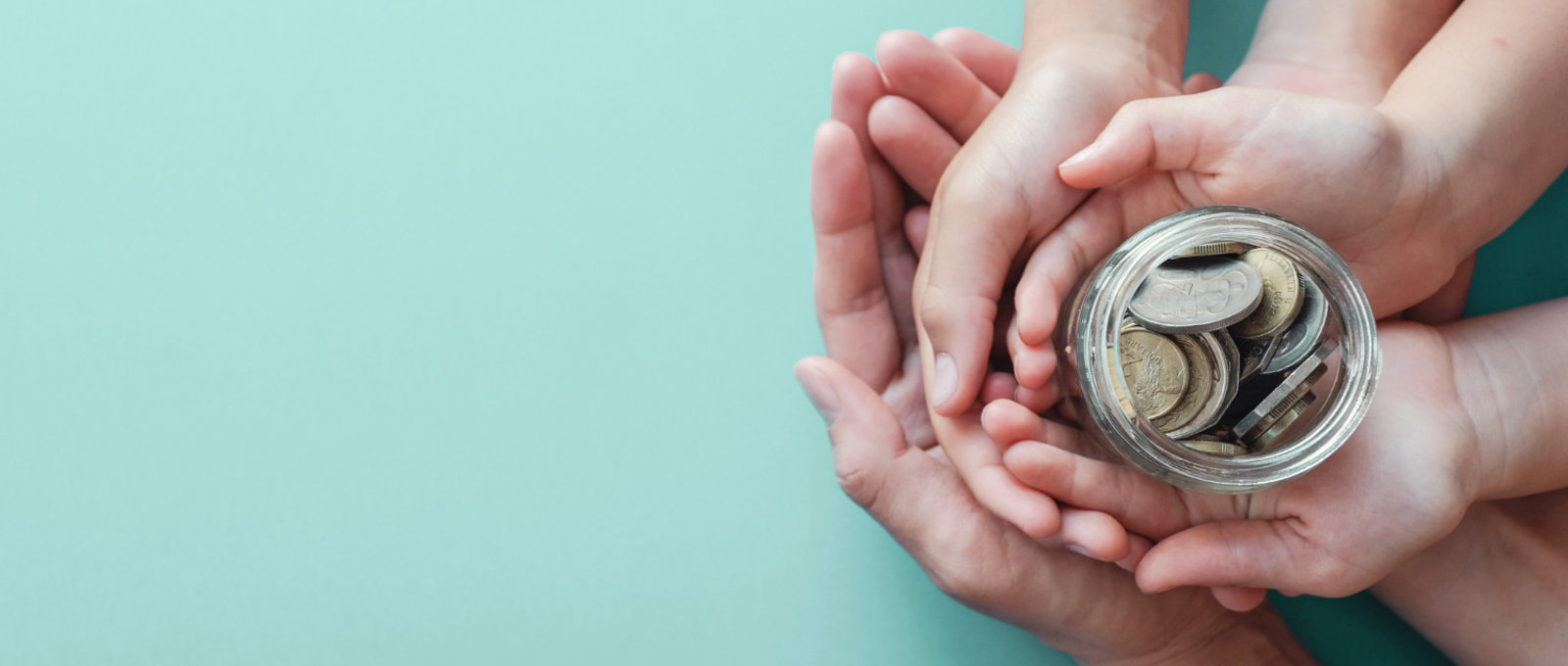 Child and adult hands on top of each other, holding a jar of money on a turquoise background