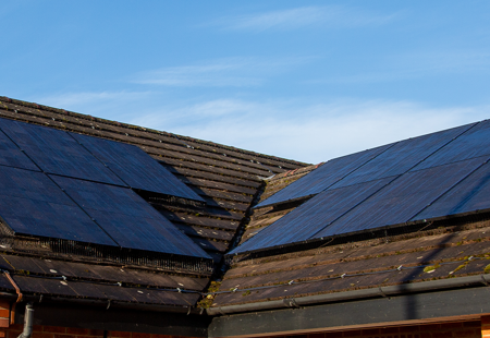 Photo of solar panels on top of a roof, blue sky