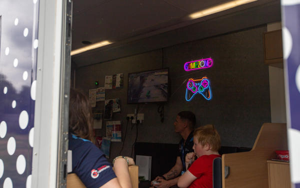 Child and colleagues playing Xbox inside a mobile van