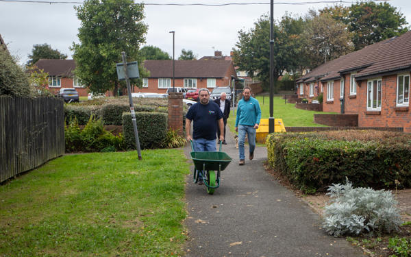 Colleague pushing an empty wheelbarrow outside