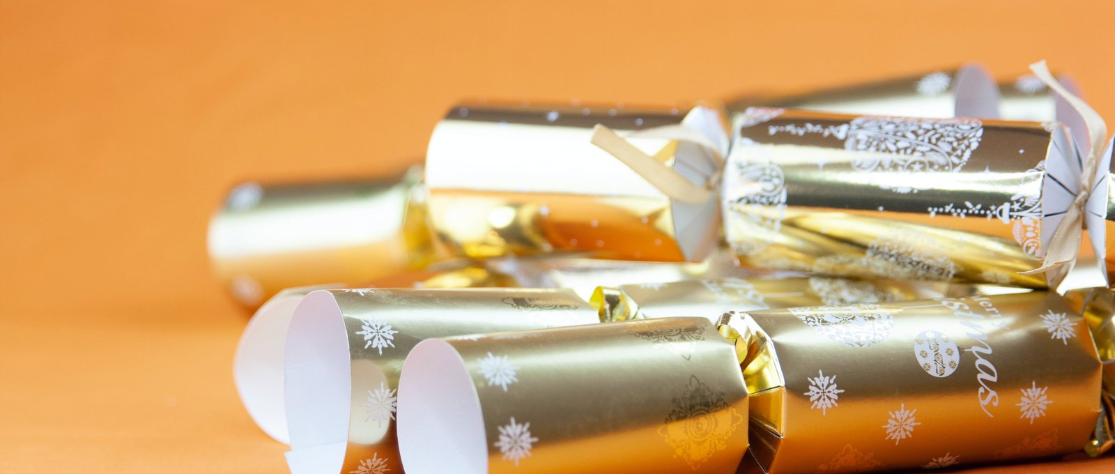 Gold Christmas crackers on an orange background